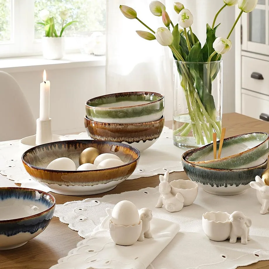 Dekket bord med blomstervase og levende lys p&aring; hvit blondeduk.