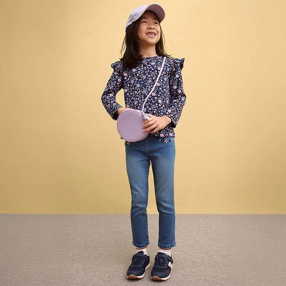 Blomstrete rysjebluse kombinert med jeans og sneakers.