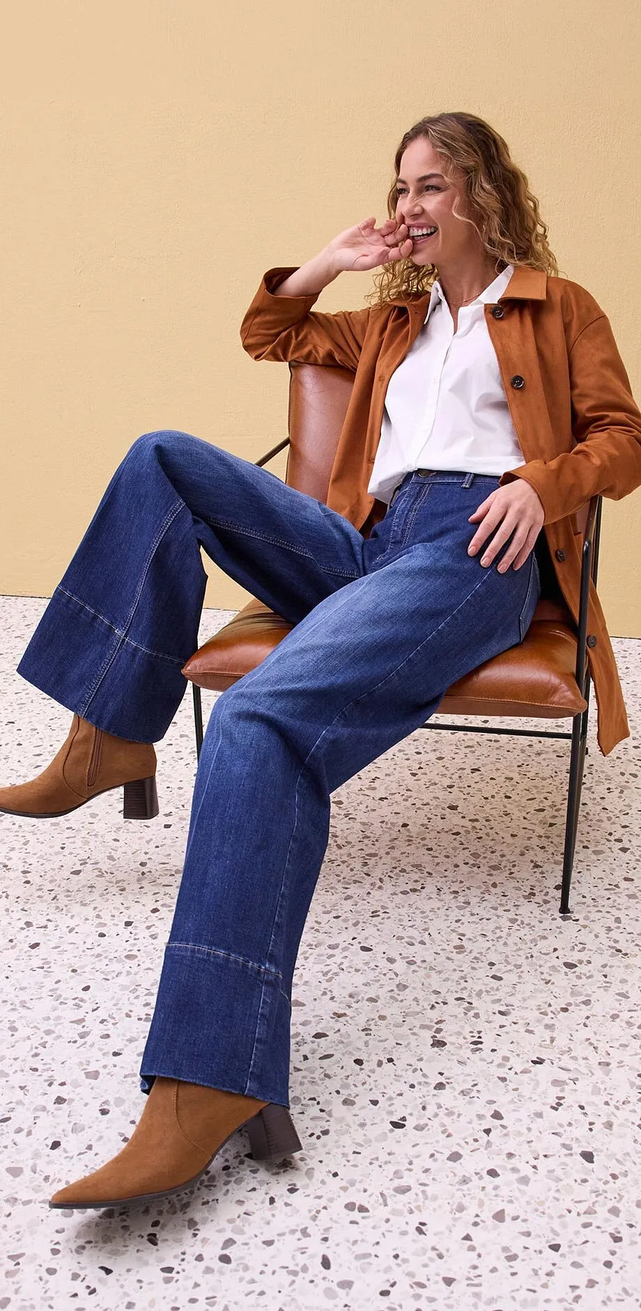 Brun skinnjakke, hvit skjorte og vide jeans.