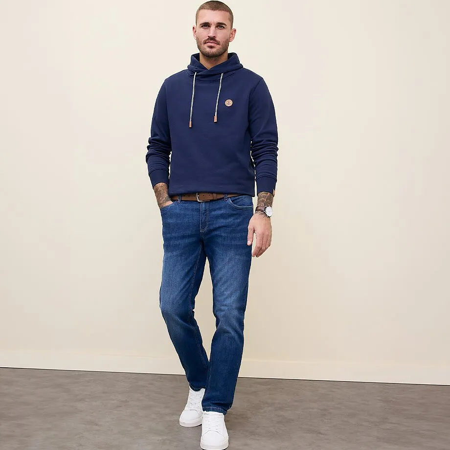 M&oslash;rkebl&aring; hettegenser, komfortable jeans og hvite joggesko.