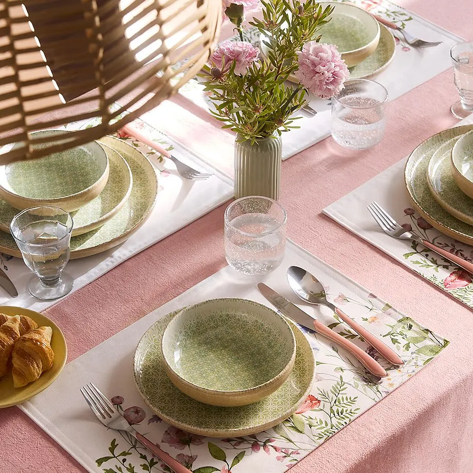 En rosa duk pynter det fint dekkede bordet.