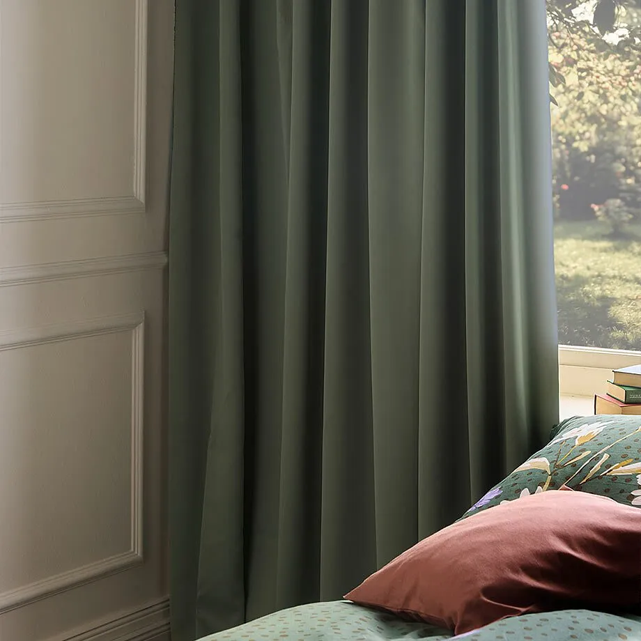 Gr&oslash;nne gardiner pynter vinduet.